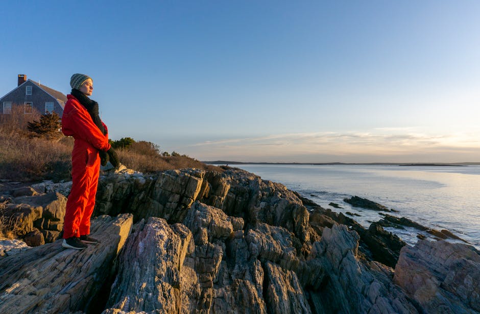 Woman meditating peacefully on a cliff overlooking the ocean at sunrise.